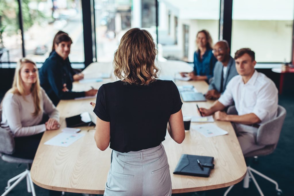 Weibliche Führungsperson vor ihrem Team in einem Meeting.
