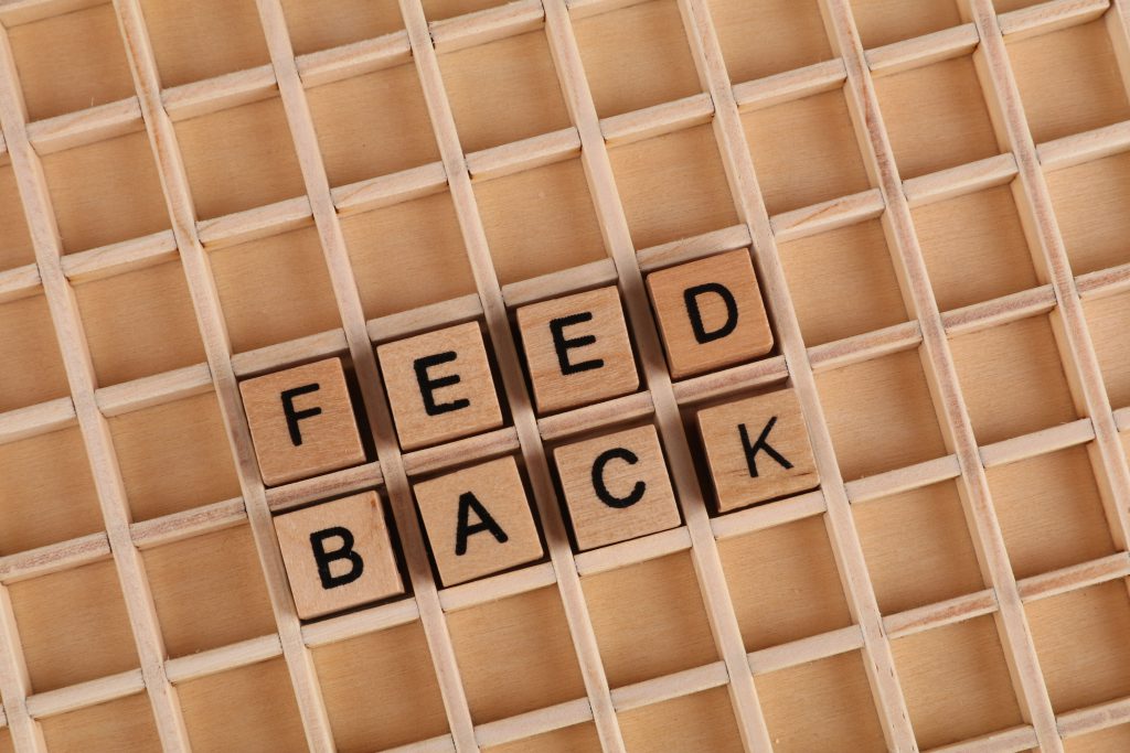 Feedback Bausteine auf einem Brett, konstruktives Feedback geben in der Kommunikation ausschlaggebend.